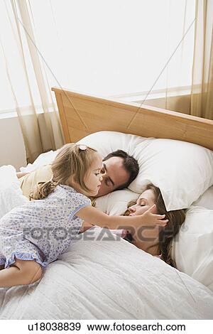 Stock Photo - Daughter waking up parents. Fotosearch
