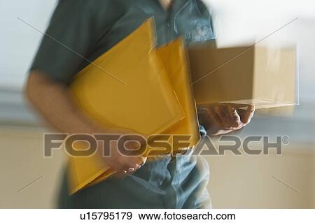Deliver man carrying boxes and envelopes View Large Photo Image Stock Photo - Deliver man carrying boxes and envelopes. Fotosearch