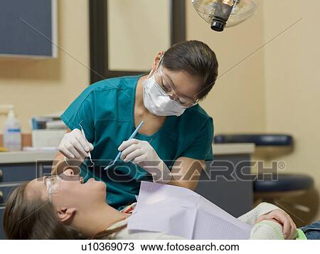 Stock Image - Dentist and patient in dental surgery. Fotosearch