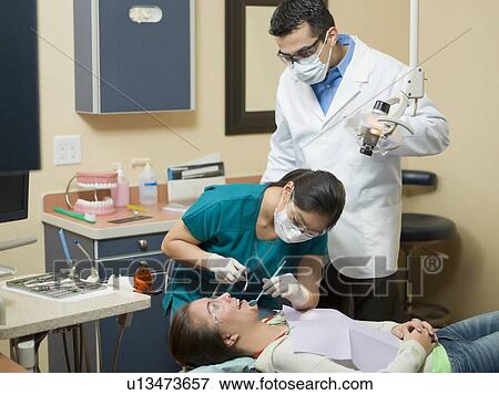 Dentists and patient in dental surgery View Large Photo Image Stock Photo - Dentists and patient in dental surgery. Fotosearch