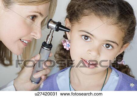 Stock Image - Doctor examining girl's (10-11) ear . Fotosearch
