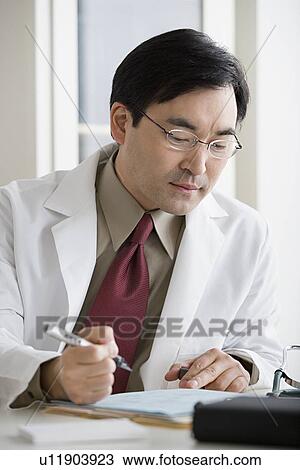 Stock Image - Doctor filling document. Fotosearch