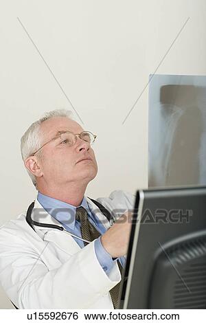 Stock Photograph - Doctor looking at x-ray image. Fotosearch