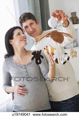 Expectant couple decorating baby room View Large Photo Image Stock Image - Expectant couple decorating baby room. Fotosearch
