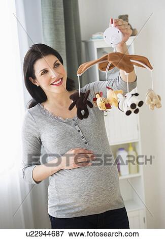Stock Photo - Expectant mother decorating baby room. Fotosearch