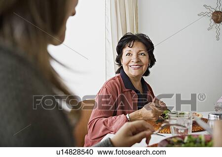 Stock Image - Family having meal together. Fotosearch