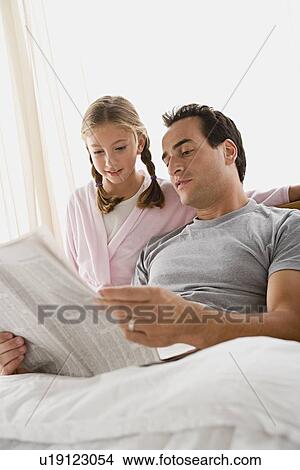 Father and daughter (12-13) reading newspaper in bedroom View Large Photo Image Picture - Father and daughter (12-13) reading newspaper in bedroom. Fotosearch