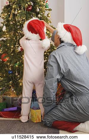 Stock Photography - Father and daughter at Christmas tree. Fotosearch