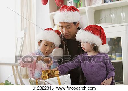 Father with two daughters (10-11) opening Christmas present View Large Photo Image Stock Photography - Father with two daughters (10-11) opening Christmas present. Fotosearch