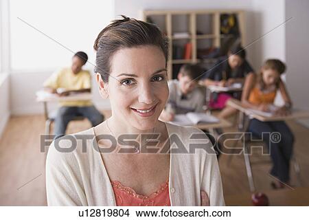 Female teacher posing in front of class View Large Photo Image Picture - Female teacher posing in front of class. Fotosearch