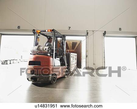 Stock Image - Forklift driver working in warehouse. Fotosearch