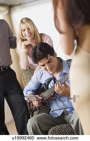 Friends at party, man playing guitar View Large Photo Image Stock Image - Friends at party, man playing guitar. Fotosearch