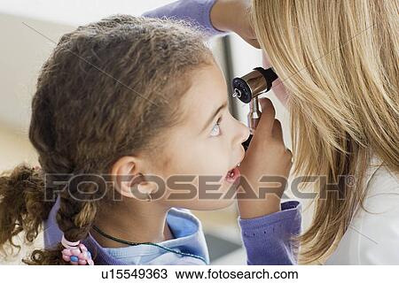 Stock Image - Girl (10-11) examining doctor's ear with otoscope. Fotosearch
