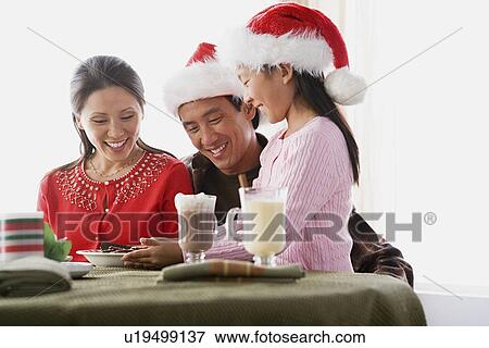 Girl (10-11) wearing Santa hat serving cookies to parents View Large Photo Image Stock Photo - Girl (10-11) wearing Santa hat serving cookies to parents. Fotosearch