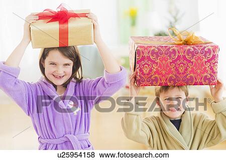 Girl (8-9) and boy (6-7) carrying christmas gifts on their heads View Large Photo Image Stock Photo - Girl (8-9) and boy (6-7) carrying christmas gifts on their heads. Fotosearch