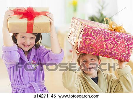 Girl (8-9) and boy (6-7) carrying christmas gifts on their heads View Large Photo Image Stock Photography - Girl (8-9) and boy (6-7) carrying christmas gifts on their heads. Fotosearch