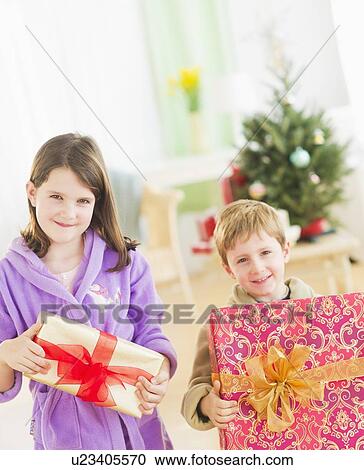 Girl (8-9) and boy (6-7) holding christmas gifts View Large Photo Image Stock Image - Girl (8-9) and boy (6-7) holding christmas gifts. Fotosearch