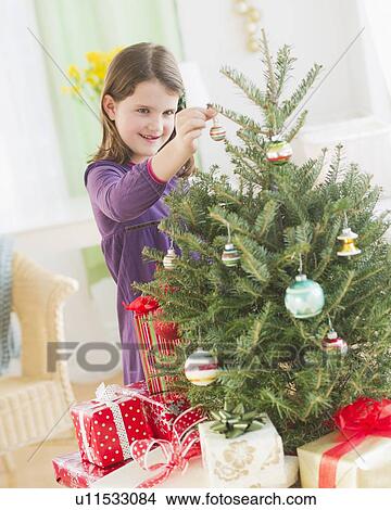 Girl (8-9) hanging decorations on Christmas tree View Large Photo Image Picture - Girl (8-9) hanging decorations on Christmas tree. Fotosearch
