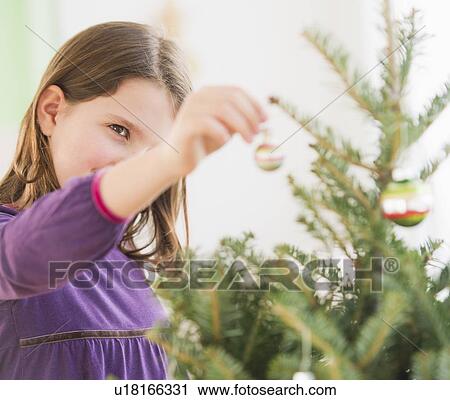 Girl (8-9) hanging decorations on Christmas tree View Large Photo Image Stock Image - Girl (8-9) hanging decorations on Christmas tree. Fotosearch