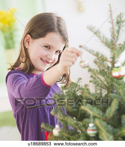 Girl (8-9) hanging decorations on Christmas tree View Large Photo Image Stock Image - Girl (8-9) hanging decorations on Christmas tree. Fotosearch