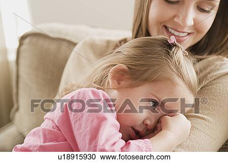 Stock Image - Girl (8-9) in mother's arms. Fotosearch