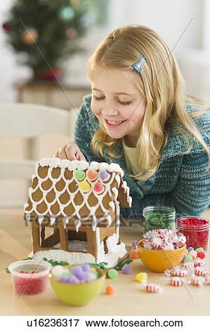 Stock Photo - Girl (8--9) making gingerbread house. Fotosearch