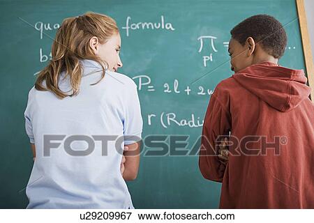 Girl and boy standing in front of blackboard with mathematical formula View Large Photo Image Stock Photo - Girl and boy standing in front of blackboard with mathematical formula. Fotosearch