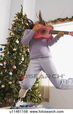 Stock Photo - Girl jumping and playing guitar. Fotosearch