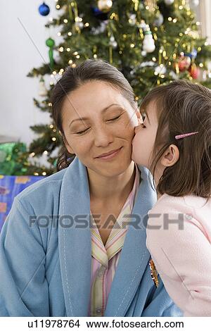 Girl kissing mother at Christmas morning View Large Photo Image Picture - Girl kissing mother at Christmas morning. Fotosearch