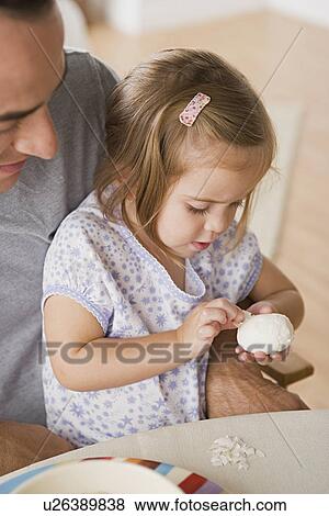 Girl sitting on father's lap peeling egg View Large Photo Image Stock Photo - Girl sitting on father's lap peeling egg. Fotosearch