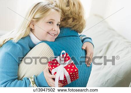 Granddaughter (8-9) hugging grandmother and holding gift View Large Photo Image Stock Image - Granddaughter (8-9) hugging grandmother and holding gift. Fotosearch