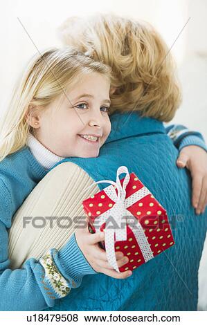 Granddaughter (8-9) hugging grandmother and holding gift View Large Photo Image Stock Photo - Granddaughter (8-9) hugging grandmother and holding gift. Fotosearch