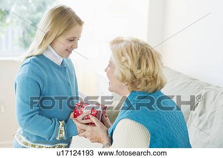 Stock Image - Granddaughter (8-9) receiving gift from grandmother. Fotosearch