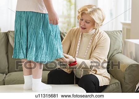 Stock Image - Grandmother with granddaughter (8-9) sewing together. Fotosearch