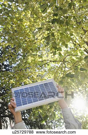 Hand holding solar panel in park View Large Photo Image Stock Photo - Hand holding solar panel in park. Fotosearch