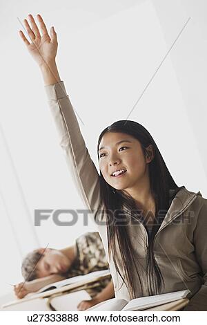Happy schoolgirl rising hand in classroom while her colleague is sleeping on his desk View Large Photo Image Stock Photo - Happy schoolgirl rising hand in classroom while her colleague is sleeping on his desk. Fotosearch
