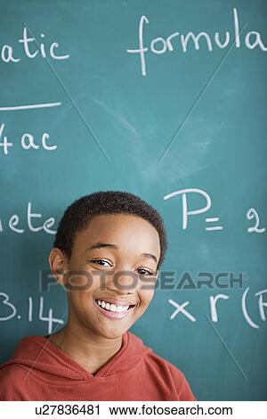Happy young boy standing against blackboard after solving mathematical equation View Large Photo Image Stock Image - Happy young boy standing against blackboard after solving mathematical equation. Fotosearch