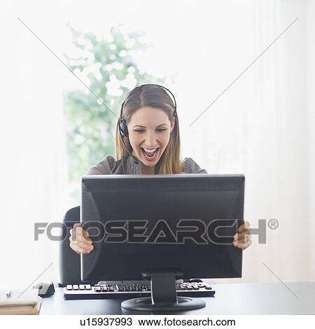 Stock Image - Happy young woman holding computer monitor. Fotosearch