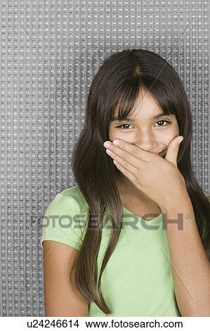 Picture - Laughing teenage girl with hands over mouth. Fotosearch