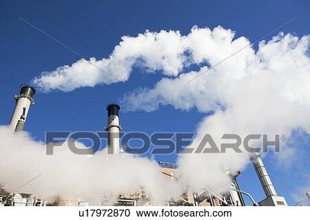 Stock Image - low angle view of factory chimneys. Fotosearch