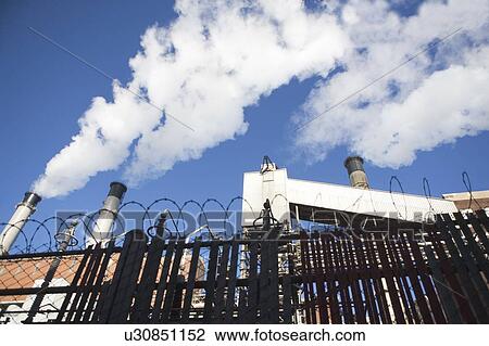 low angle view of factory chimneys behind fence View Large Photo Image Stock Image - low angle view of factory chimneys behind fence. Fotosearch