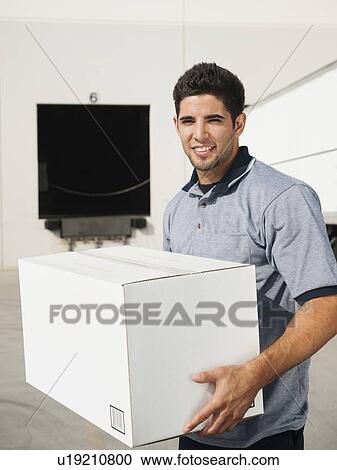 Man carrying box in warehouse View Large Photo Image Stock Image - Man carrying box in warehouse. Fotosearch