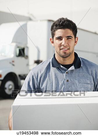 Stock Photo - Man carrying box in warehouse. Fotosearch