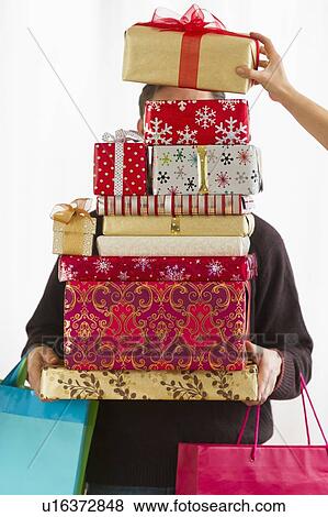 Man carrying stack of Christmas presents, studio shot View Large Photo Image Stock Photo - Man carrying stack of Christmas presents, studio shot. Fotosearch