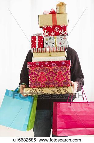 Man carrying stack of Christmas presents, studio shot View Large Photo Image Stock Photography - Man carrying stack of Christmas presents, studio shot. Fotosearch