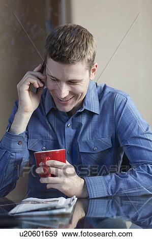 Stock Photo - Man drinking coffee and talking on phone. Fotosearch