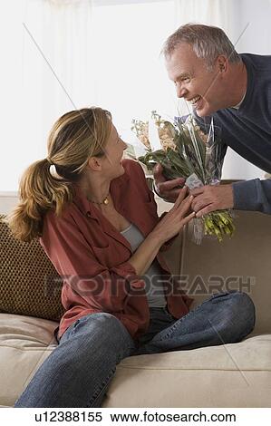 Stock Photography - Man giving flowers to wife. Fotosearch