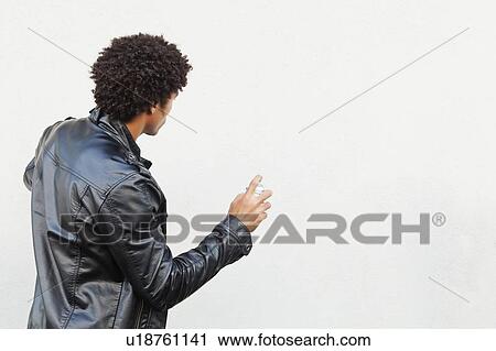 Man holding spray paint against white wall, studio shot View Large Photo Image Stock Image - Man holding spray paint against white wall, studio shot. Fotosearch