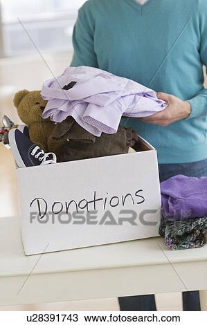 Stock Image - Man packing clothes for donation. Fotosearch