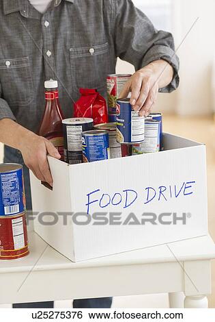 Stock Photograph - Man packing food for donation. Fotosearch